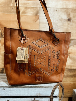 Brown leather tote bag with embossed design on a wooden surface