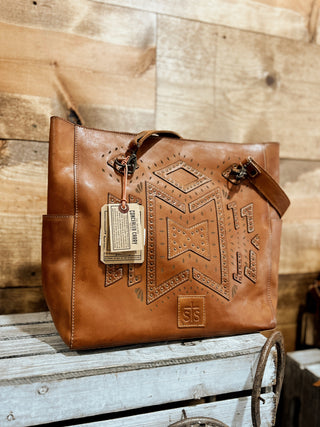 Brown leather handbag with embossed design on a wooden surface