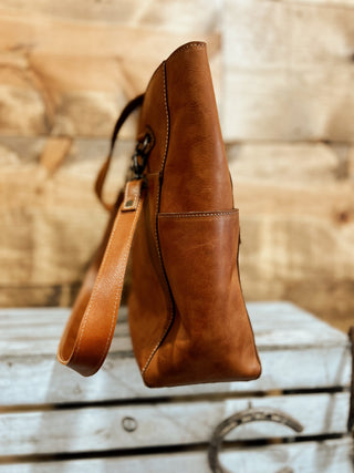 Brown leather handbag on a wooden surface with a blurred background