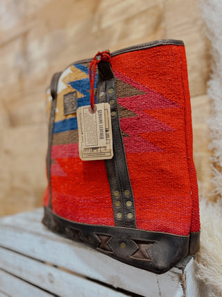 Handbag with a geometric pattern and leather accents on a wooden surface