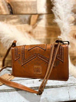 Brown leather handbag with intricate designs on a wooden surface