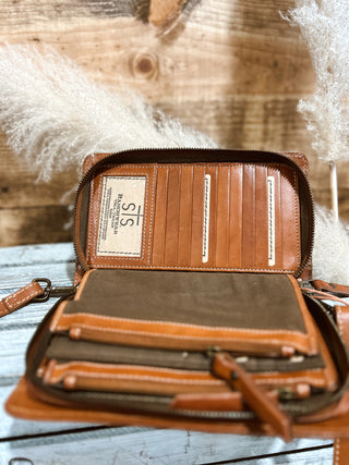 Brown leather wallet with visible brand label on a wooden surface