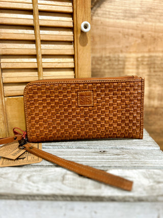 Brown woven wallet with a strap on a wooden surface