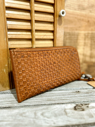 Brown woven wallet on a wooden surface with a wooden panel background