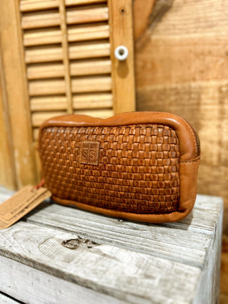 Brown woven pouch on a wooden surface with a blurred background