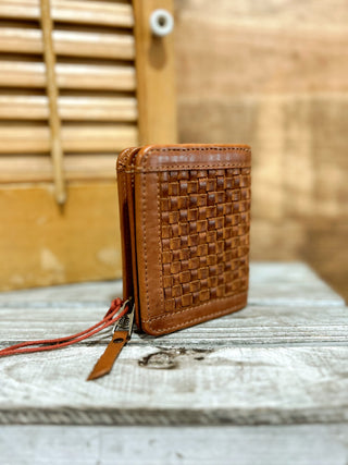 Brown woven leather wallet on a textured surface with a blurred wooden background