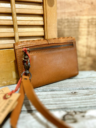 Brown leather wallet with strap on a textured surface