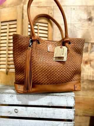 Brown woven handbag with a visible brand tag on a wooden surface