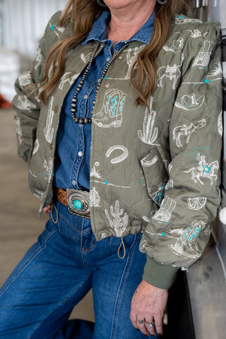 Person wearing a green jacket with cowboy pattern, blue shirt, and jeans.