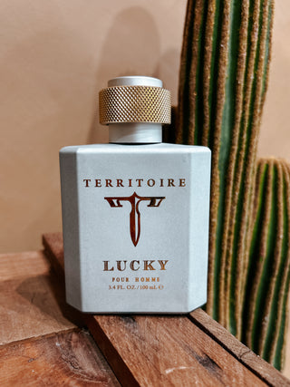 Perfume bottle labeled 'Territoire Lucky' on a wooden surface with a cactus in the background