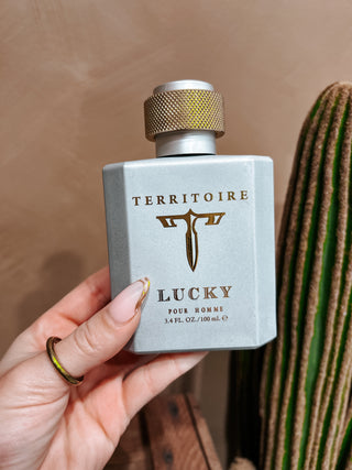 Territoire Lucky pour Homme perfume bottle held by a hand with a cactus in the background