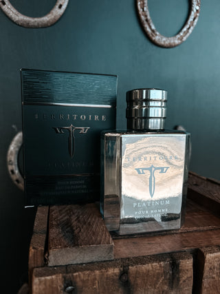 Territoire perfume bottle and packaging on a wooden surface with a dark green wall background