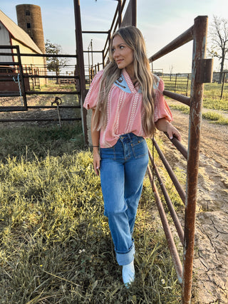 Woman standing by a fence on a farm with a barn and silo in the background