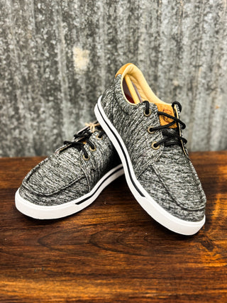 Pair of gray sneakers with white soles on a wooden surface with a textured gray background