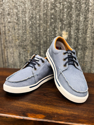 Pair of blue casual shoes on a wooden surface with a textured wall background