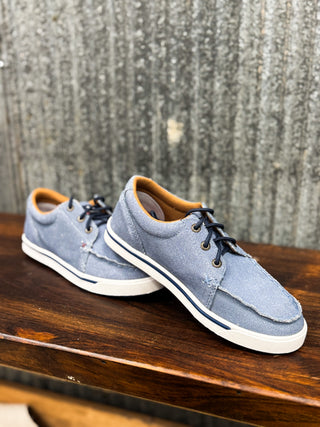 Pair of blue sneakers with brown accents on a wooden surface with a textured gray background