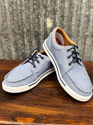 Pair of blue casual shoes on a wooden surface with a textured wall background