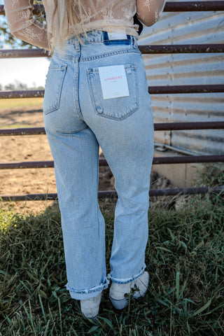 Person wearing light blue jeans with a visible brand label, standing outdoors.