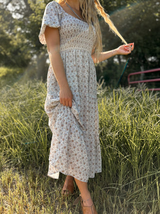 Woman in a floral dress standing in a grassy field