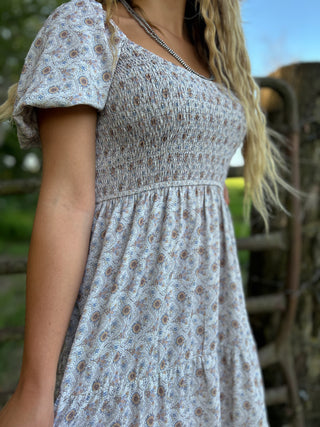 Woman wearing a floral dress with a blurred outdoor background