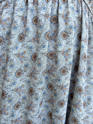 Close-up of patterned fabric with floral design in brown and blue on a light background