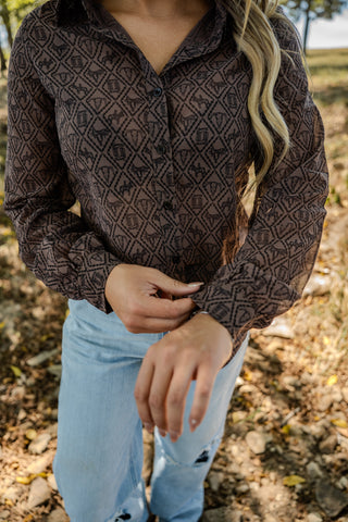 Person wearing a patterned shirt and light blue jeans outdoors