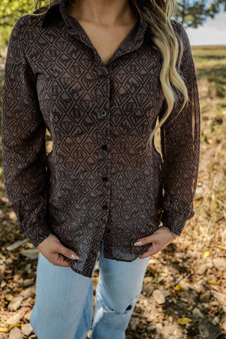 Person wearing a patterned brown shirt outdoors