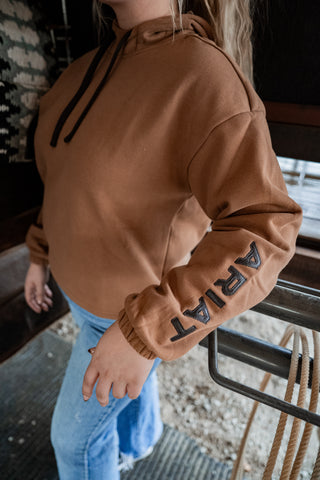 Person wearing a brown hoodie with 'ART' text, standing on a staircase.
