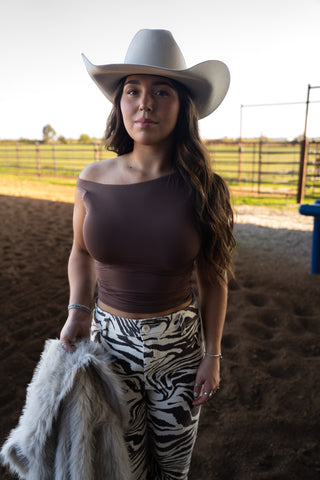 Woman wearing a cowboy hat and zebra print pants in an outdoor setting