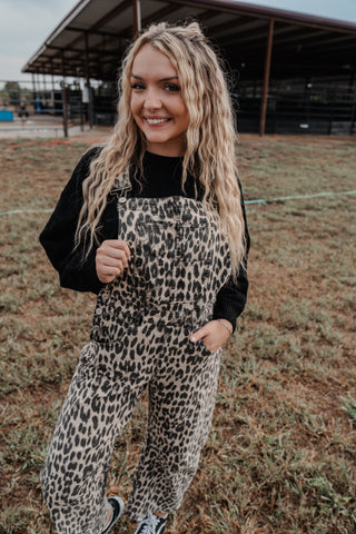 Woman wearing leopard print overalls and a black top in an outdoor setting