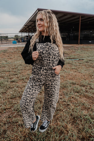 Person wearing a leopard print jumpsuit standing in an open field.