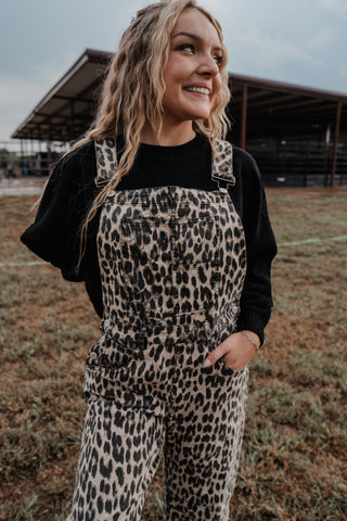 Woman wearing leopard print overalls and a black shirt in an outdoor setting