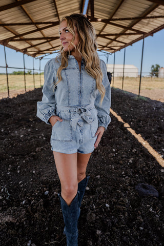 Woman in denim outfit standing in a rural setting with a barn in the background