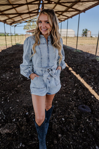 Woman in a denim outfit standing in an outdoor setting with a clear sky.