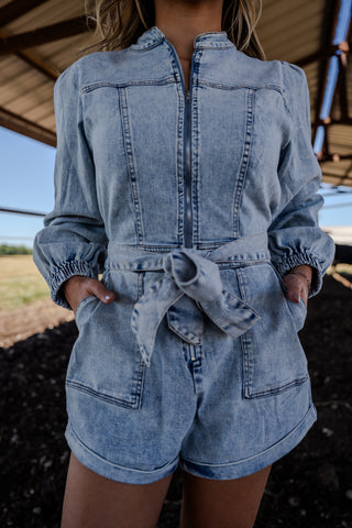 Person wearing a denim romper with a blurred background