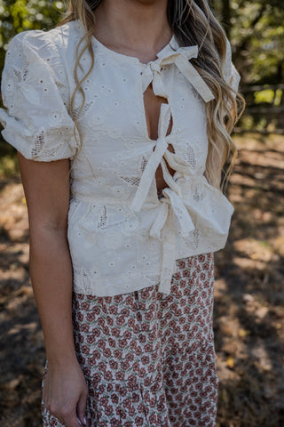 Woman wearing a white lace top with a floral skirt in a natural setting
