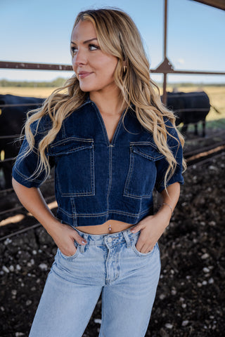 Woman wearing a denim jacket and jeans standing in an outdoor setting.