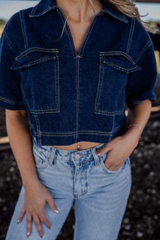 Person wearing a blue denim jacket and jeans with a blurred background