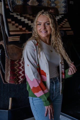 Woman wearing a colorful cardigan in front of patterned rugs