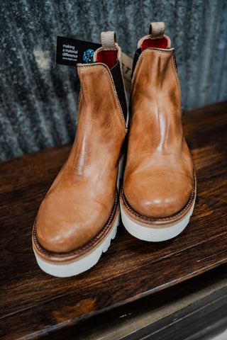 Pair of brown leather boots on a wooden surface with a blurred background