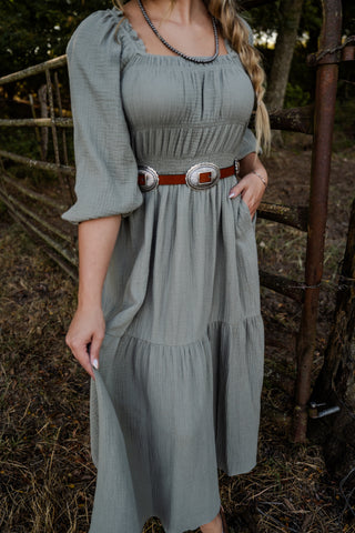 Woman wearing a green dress with a belt in an outdoor setting