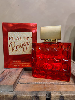 Red perfume bottle with gold cap and 'Flaunt Rouge' packaging on a wooden surface.