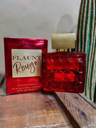 Red 'Flaunt Rouge' perfume bottle and packaging on a wooden surface.