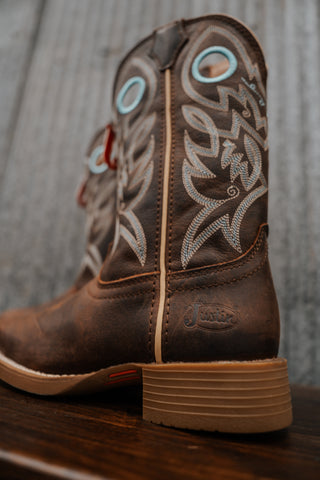 Brown cowboy boot with intricate white and turquoise embroidery on a wooden surface.