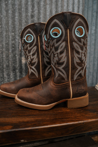 Pair of brown cowboy boots with intricate designs on a wooden surface.