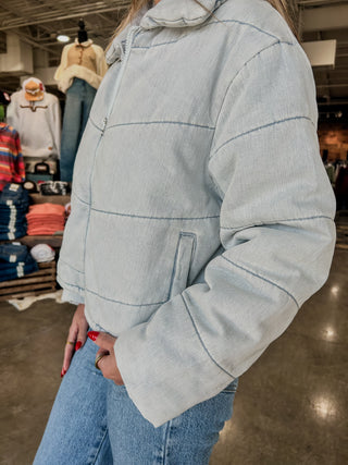 Person wearing a light blue pullover with a hood in a store setting