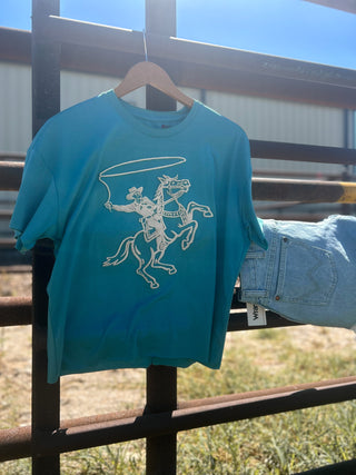 Turquoise t-shirt with white graphic design on a hanger against a fence background