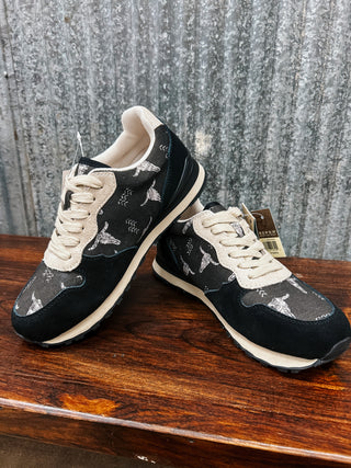 Black and white sneakers with paw print pattern on a wooden surface