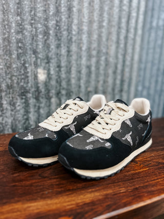 Black sneakers with white patterns on a wooden surface and textured wall background