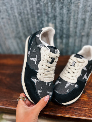 Black sneakers with white patterns on a wooden surface